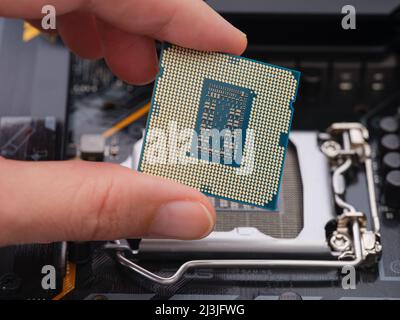 Tambov, Fédération de Russie - 07 avril 2022 Une femme tenant un processeur Intel Core i5 de 11th générations dans sa main sur un socket LGA 1200 sur une mère Banque D'Images