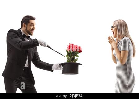 Magicien faisant un tour magique avec des fleurs et un chapeau devant une femme surprise isolée sur fond blanc Banque D'Images