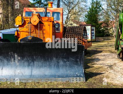 Ancien bulldozer orange puissant avec godet noir à l'avant pour les travaux de réparation sur route. Banque D'Images