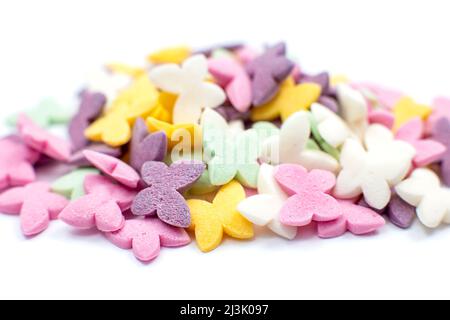 Un bouquet de papillons multicolores, saupoudrés de sucre dans des couleurs pastel, se trouve sur un fond blanc. Banque D'Images