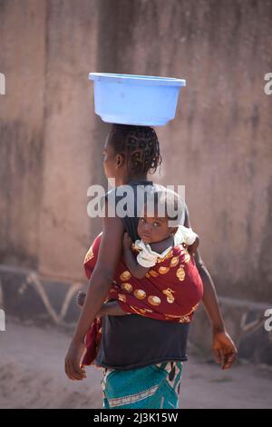 Une femme congolaise avec bébé porte un récipient en plastique sur sa tête; Kinshasa, République démocratique du Congo. Banque D'Images