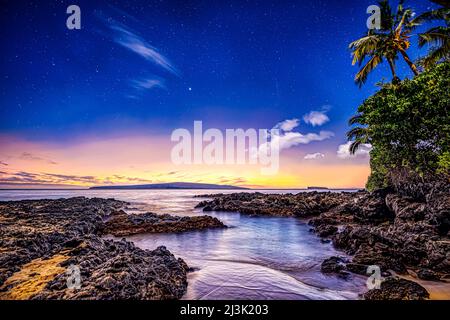 Paysage dans un paradis hawaïen à Makena Cove au coucher du soleil avec des roches sauvages et une végétation luxuriante bordant le rivage, et des étoiles dans le ciel clair Banque D'Images