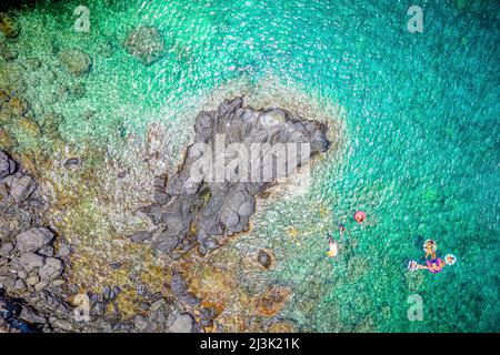 Vue de drone directement au-dessus des nageurs dans l'eau claire et turquoise de l'océan Pacifique le long de la côte sauvage de Maui, Hawaii, États-Unis Banque D'Images