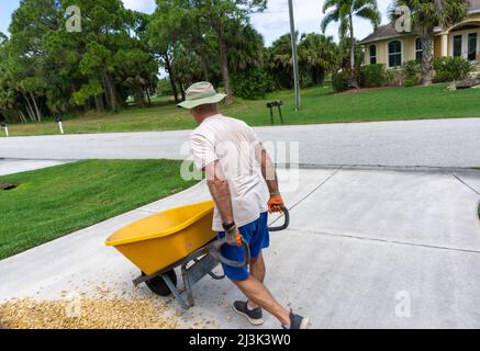 Homme marchant avec une brouette pleine Banque D'Images