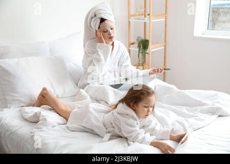 Mère fatiguée avec sa petite fille essayant de travailler dans la chambre Banque D'Images