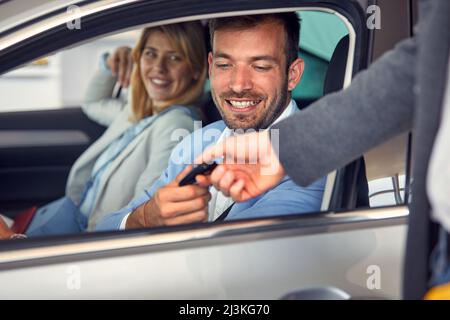 Homme et femme heureux d'acheter une nouvelle voiture et de prendre la clé de voiture Banque D'Images