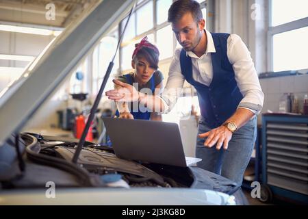 Les travailleurs masculins et féminins détectent un problème de service automobile Banque D'Images