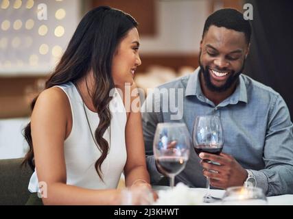 Il semble que cette date se passe bien. Petit cliché d'un jeune couple affectueux en train de se réunir dans un restaurant. Banque D'Images