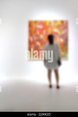 Personnes regardant des peintures sur le mur blanc dans la galerie d'exposition d'art. Arrière-plan flou. Banque D'Images