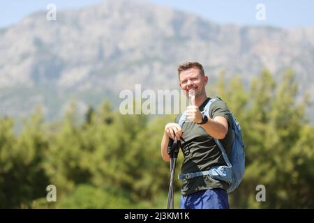 Homme souriant avec bâtons de marche scandinaves sur fond de montagne Banque D'Images