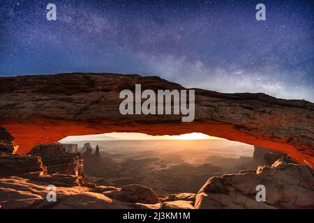 Une image rare de la voie laiteuse et de la lune qui s'élève pour éclairer le paysage désertique sous Mesa Arch, dans le parc national de Canyonlands Banque D'Images