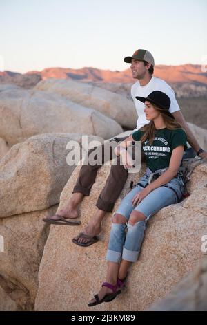 Un jeune couple prendre au coucher du soleil après l'ascension de la route de l'Œil sur Rock Cyclope dans Joshua Tree National Park. Banque D'Images