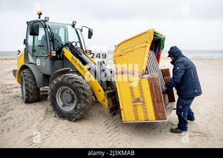 Hooksiel, Allemagne. 05th avril 2022. Les employés de Wangerland Touristik GmbH utilisent une chargeuse sur pneus pour installer des chaises de plage sur une étendue de plage par temps pluvieux. Les préparatifs pour le début de la saison sont en cours sur la côte de la mer du Nord de Basse-Saxe. Credit: Hauke-Christian Dittrich/dpa/Alay Live News Banque D'Images