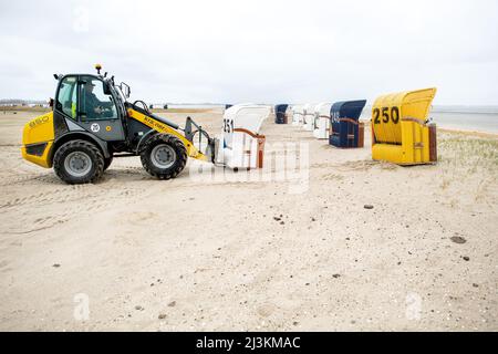 Hooksiel, Allemagne. 05th avril 2022. Les employés de Wangerland Touristik GmbH utilisent une chargeuse sur pneus pour installer des chaises de plage sur une étendue de plage par temps pluvieux. Les préparatifs pour le début de la saison sont en cours sur la côte de la mer du Nord de Basse-Saxe. Credit: Hauke-Christian Dittrich/dpa/Alay Live News Banque D'Images