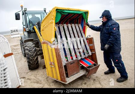 Hooksiel, Allemagne. 05th avril 2022. Les employés de Wangerland Touristik GmbH utilisent une chargeuse sur pneus pour installer des chaises de plage sur une étendue de plage par temps pluvieux. Les préparatifs pour le début de la saison sont en cours sur la côte de la mer du Nord de Basse-Saxe. Credit: Hauke-Christian Dittrich/dpa/Alay Live News Banque D'Images