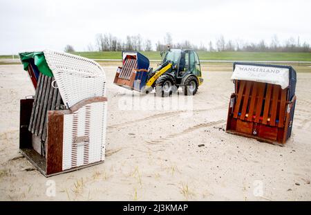 Hooksiel, Allemagne. 05th avril 2022. Les employés de Wangerland Touristik GmbH utilisent une chargeuse sur pneus pour installer des chaises de plage sur une étendue de plage par temps pluvieux. Les préparatifs pour le début de la saison sont en cours sur la côte de la mer du Nord de Basse-Saxe. Credit: Hauke-Christian Dittrich/dpa/Alay Live News Banque D'Images