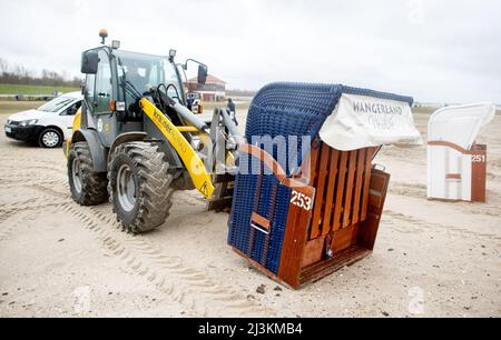 Hooksiel, Allemagne. 05th avril 2022. Les employés de Wangerland Touristik GmbH utilisent une chargeuse sur pneus pour installer des chaises de plage sur une étendue de plage par temps pluvieux. Les préparatifs pour le début de la saison sont en cours sur la côte de la mer du Nord de Basse-Saxe. Credit: Hauke-Christian Dittrich/dpa/Alay Live News Banque D'Images