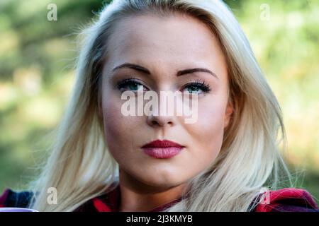 Belle jeune femme sérieuse avec une expression sereine regardant tranquillement la caméra dans un gros plan court en plein air tête tourné dans un parc Banque D'Images