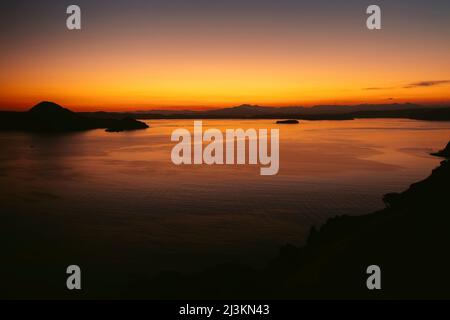 Jaune vif et orange du coucher de soleil sur l'océan et des îles silhouetées dans le parc national de Komodo dans l'archipel de Komodo Banque D'Images