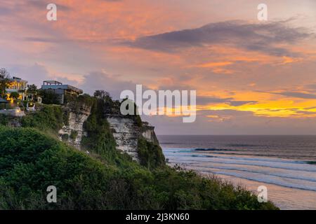 Maisons de plage en bord de mer sur les falaises de la péninsule de Bukit à la plage d'Uluwatu, donnant sur l'océan Indien dans le sud de Bali au coucher du soleil Banque D'Images