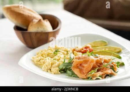 œufs brouillés avec saumon fumé et petit déjeuner sain à l'avocat sur la table du restaurant Banque D'Images