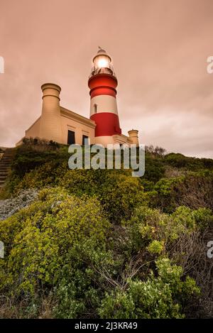 Phare de Cape Agulhas illuminé au crépuscule, parc national d'Agulhas; Cape Agulhas, Cap occidental, Afrique du Sud Banque D'Images