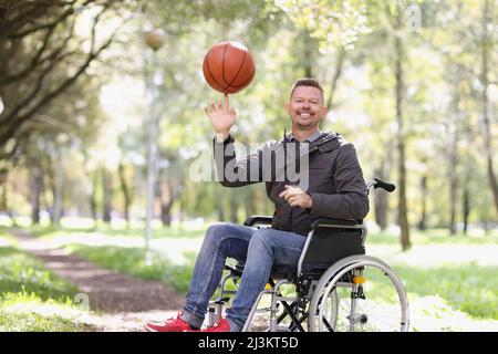 Homme souriant en fauteuil roulant tenant un ballon de près Banque D'Images