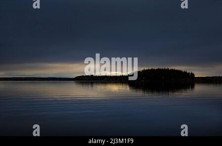 Silhoueté arbres le long d'un rivage et lumière du coucher de soleil se reflète dans l'eau tranquille vue de Meir Road dans Lake Country, à l'ouest de Prince George, ... Banque D'Images