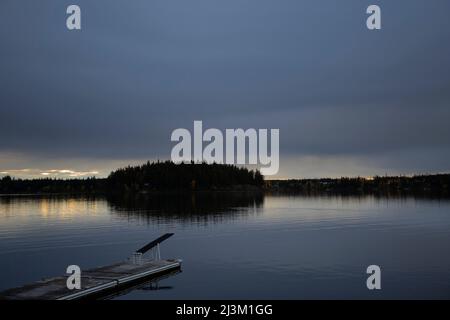 Amarrez et silhoueté des arbres le long d'un rivage et de la lumière du coucher de soleil se reflète dans l'eau tranquille vue de Meir Road dans le lac Country, à l'ouest de Prince... Banque D'Images