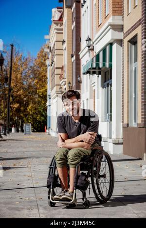 Portrait extérieur d'un jeune paraplégique dans son fauteuil roulant sur un passage de la ville lors d'une belle journée d'automne; Edmonton, Alberta, Canada Banque D'Images