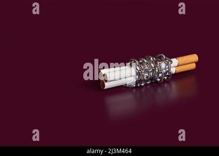 Dépendance à la nicotine. Trois cigarettes rembobinées par une chaîne Banque D'Images