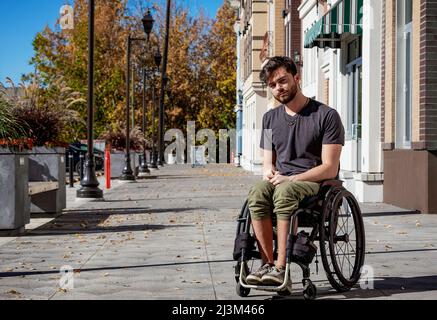 Portrait extérieur d'un jeune paraplégique dans son fauteuil roulant sur un passage de la ville lors d'une belle journée d'automne; Edmonton, Alberta, Canada Banque D'Images