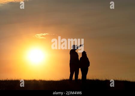 Silhouette d'un couple amoureux pendant que le soleil se couche derrière eux, parc national des Prairies; Val Marie, Saskatchewan, Canada Banque D'Images