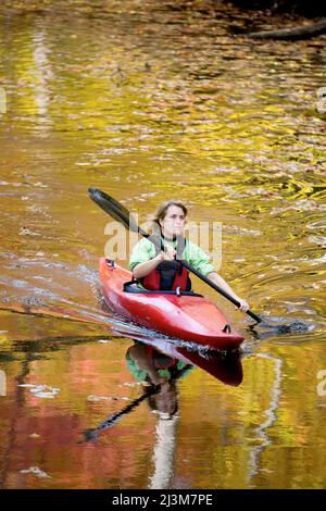 Une jeune femme fait du kayak sur le canal C&O à l'automne; Chesapeake et Ohio Canal National Park, Cabin John, MD Banque D'Images