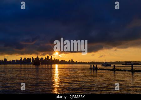 Le soleil doré se dresse derrière les gratte-ciel et l'horizon du centre-ville de Vancouver, tandis que sunbeam réfléchit sur l'eau de Burrard Inlet Banque D'Images