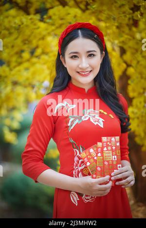 Ho Chi Minh ville, Vietnam: Portrait d'une brillante fille vietnamienne dans un rouge ao dai pour accueillir le nouvel an traditionnel vietnamien Banque D'Images