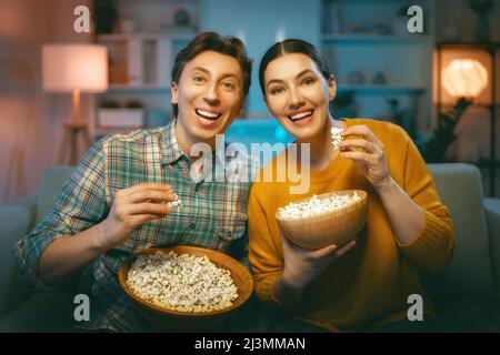 Bonne famille regardant le projecteur, la télévision, des films avec pop-corn le soir à la maison. Couple passant du temps ensemble. Banque D'Images