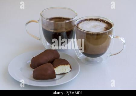 Caillé de fromage glacé. Gâteaux faits maison avec fromage cottage en glaçage au chocolat sur une assiette et mugs en verre avec café. Banque D'Images