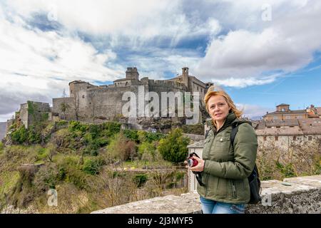 Une femme blonde avec ses cheveux soufflant dans le vent admire la vue près du château Castello di Bardi, Parme, Italie Banque D'Images