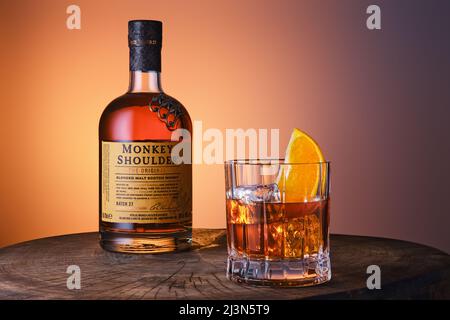 Avril 8,2022, Minsk, Belarus - bouteille et verre avec Monkey Shoulder mélange de whisky malt scotch sur fond bleu orange dégradé Banque D'Images