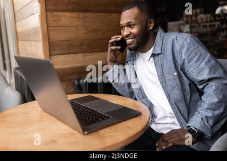 Portrait en gros plan du jeune homme d'affaires afro-américain qui parle au téléphone portable au bureau. Il demande à être calme, il a une affaire très importante Banque D'Images