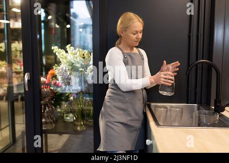 Fleuriste ouvrier lave les vases dans le lavabo et les remplit d'eau pour les fleurs, concept de fleuriste Banque D'Images