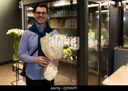 acheteur satisfait de bouquets dans un fleuriste sur fond d'un réfrigérateur avec fleurs Banque D'Images