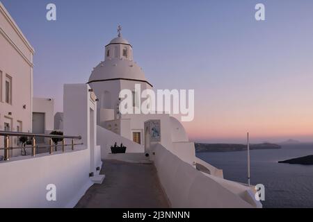 Santorini, Grèce - 10 mai 2021 : une allée menant à une belle église blanche et au volcan de Santorini en arrière-plan Banque D'Images