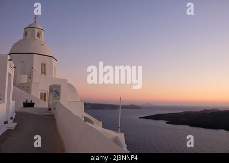 Santorini, Grèce - 10 mai 2021 : une allée menant à une belle église blanche et au volcan de Santorini en arrière-plan Banque D'Images