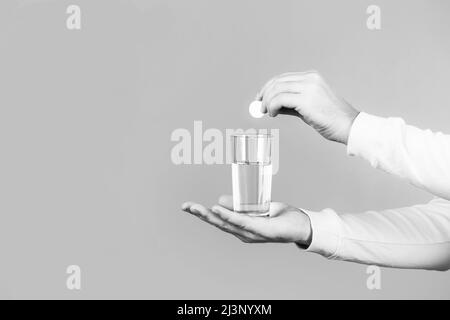 Pilule blanche et un verre d'eau dans les mains de l'homme. Concept de santé. Gros plan de l'homme tenant une pilule. Verre de comprimé d'eau. Verre avec comprimé d'éperescence Banque D'Images