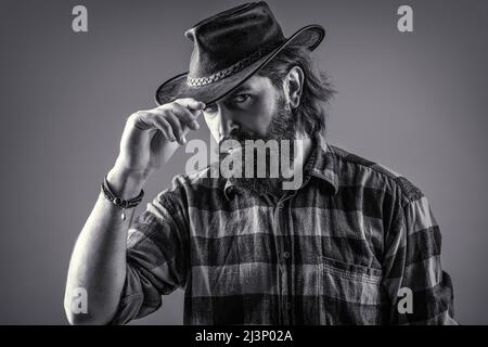 Cow-boys non rasés. Cow-boy américain. Chapeau de cowboy en cuir. Portrait d'un jeune homme portant un chapeau de cow-boy. Cowboys en chapeau. Jolie macho barbu Banque D'Images