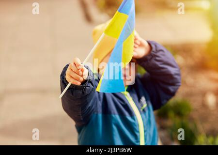 Un petit garçon patriotique porte le drapeau ukrainien. Tenez-vous avec l'Ukraine. Soutenir l'Ukraine. Arrêter le concept d'agression russe. Arrêter la guerre en Ukraine. Priez pour l'Ukraine Banque D'Images