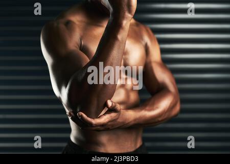 Renforcer les muscles autour de vos articulations. Photo en studio d'un homme méconnaissable examinant une blessure au coude pendant son entraînement. Banque D'Images