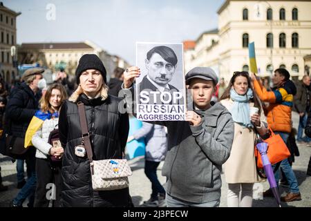 Munich, Allemagne. 09th avril 2022. Garçon avec un signe montrant Poutine comme Hitler lit: ' Stop Russain agression '. Le 9 avril, 2022 mille personnes se sont rassemblées à Munich, en Allemagne, pour protester contre l'invasion russe en Ukraine et se sont remébérées des morts du massacre de Bucha. (Photo par Alexander Pohl/Sipa USA) crédit: SIPA USA/Alay Live News Banque D'Images